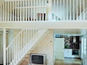 Une maison à deux étages avec un escalier, une cuisine avec un dosseret carrelé et un téléviseur situé au rez-de-chaussée.