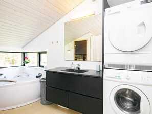 A modern bathroom with a built-in washing machine, a vanity with a sink, and a large mirror.