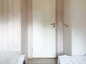 Ein Schlafzimmer mit einem Holzschrank, einem Bett mit weißer Daunendecke und einer Tür mit Griff.