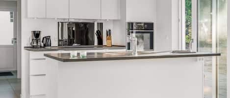 Una cocina moderna con armarios blancos, una isla central y un amplio ventanal.