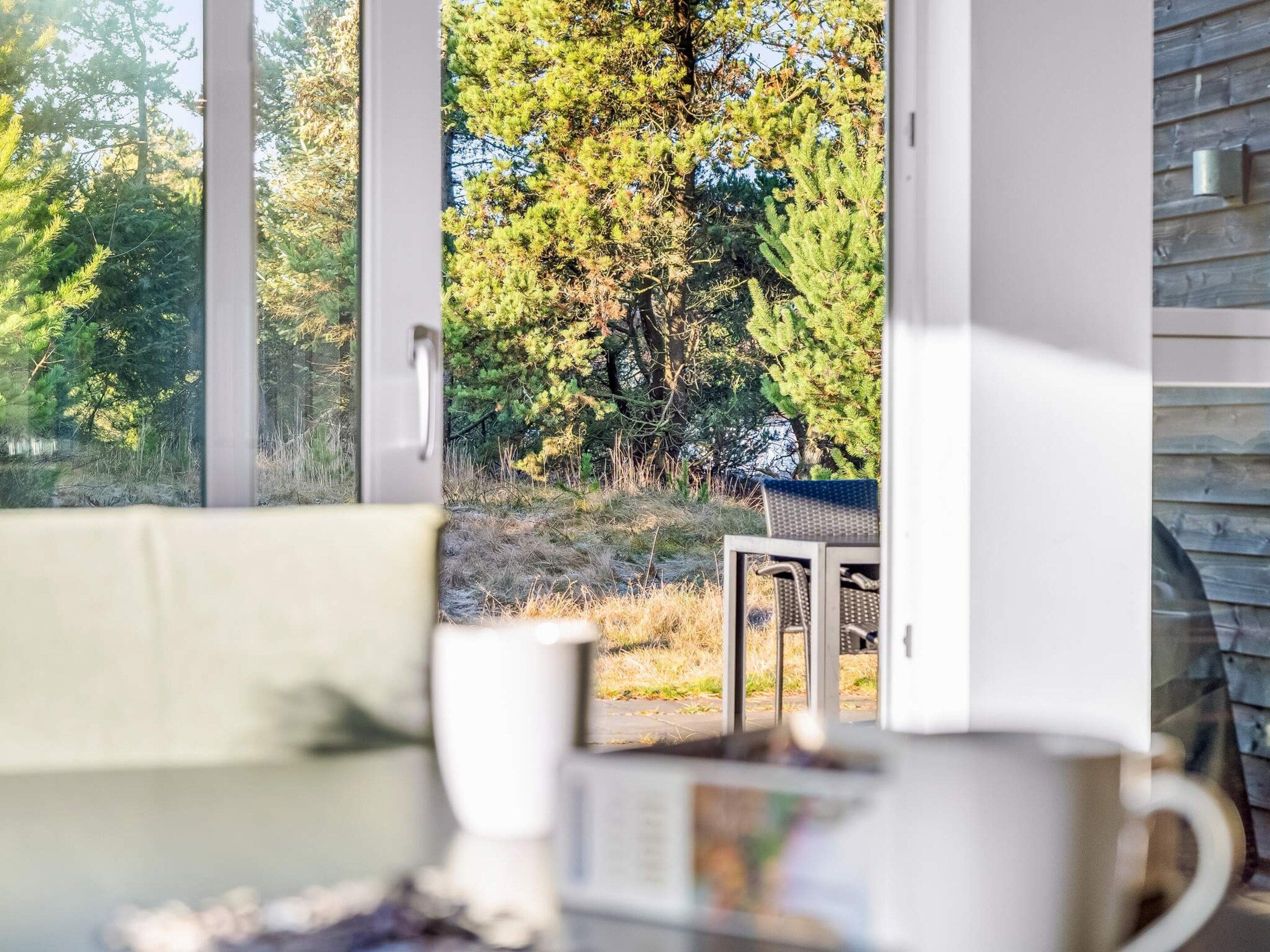 A room with a large window offering a view of a forested area.