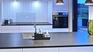 A modern kitchen with a black countertop, stainless steel sink, and overhead pendant lighting. - 8 Person Holiday Home in Sjolund-by Traum (Sjølund)
