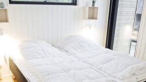 A neatly made bed in a room with white walls and a window. - 8 Person Holiday Home in Sjolund-by Traum (Sjølund)
