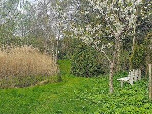 A garden with a bench, lush greenery, and flowering trees. - 5 Person Holiday Home in Jaegerspris (Jægerspris)