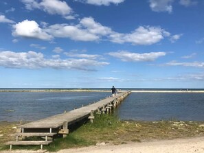 A wooden pier extending into calm waters with a clear sky and distant horizon.