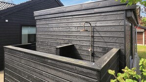 A modern outdoor shower area with a wooden wall and a metal showerhead. - 5 Star Holiday Home in Hadsund (Hadsund)