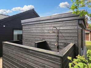 A modern outdoor shower area with a wooden wall and a metal showerhead. - 5 Star Holiday Home in Hadsund (Hadsund)