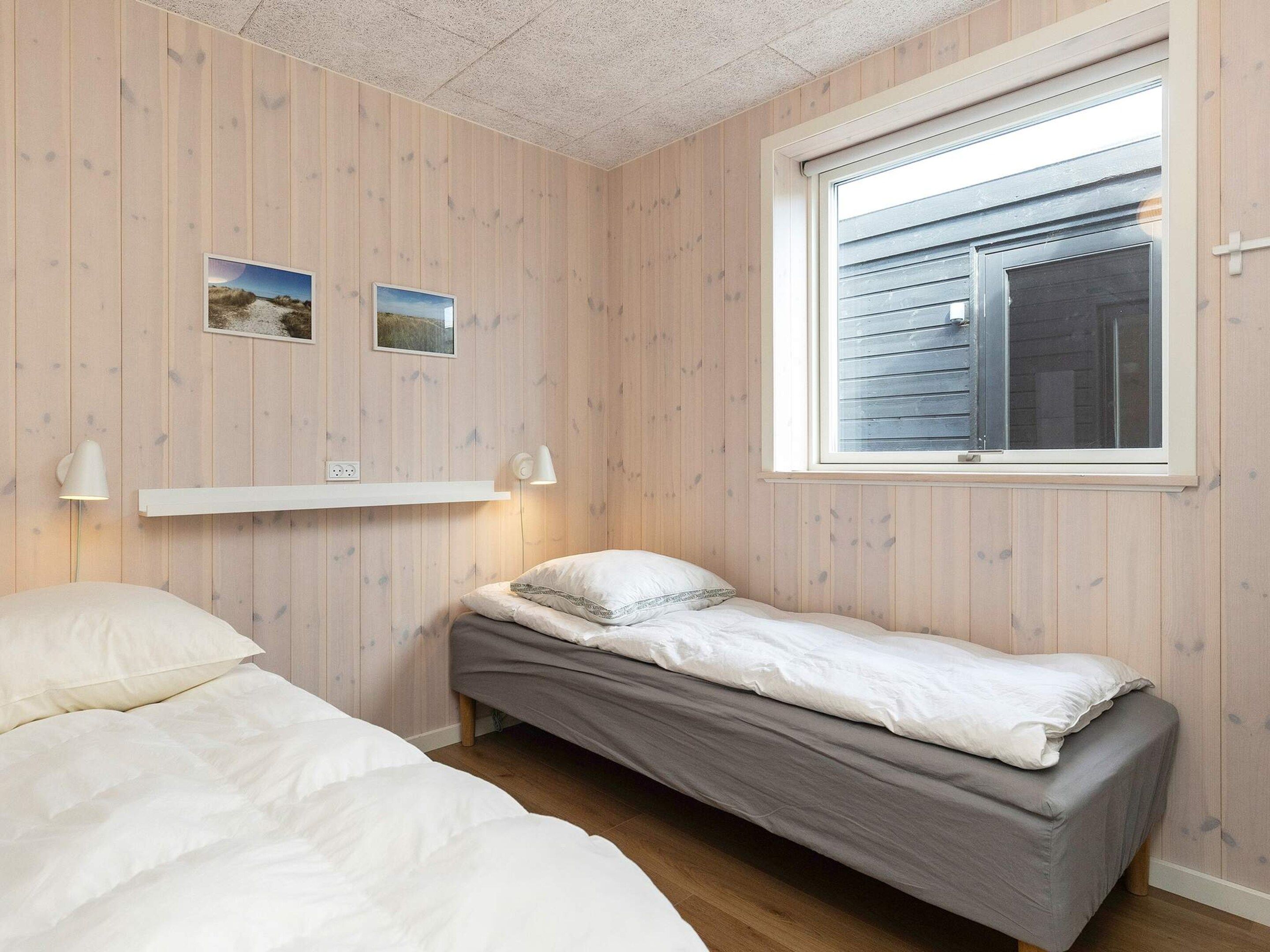 A bedroom with two beds, a window, and wall-mounted shelves.