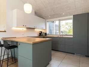 A modern kitchen with a central island, bar stools, a window with a view, and built-in cabinets.