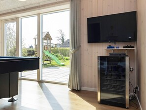 A living room with a pool table, a television mounted on the wall, and a sliding glass door leading to a patio with a slide. - 5 Star Holiday Home in Hadsund (Hadsund)