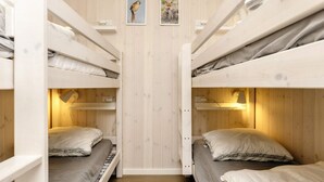 A bunk bed room with wooden walls, two framed pictures, and bedside lamps. - 5 Star Holiday Home in Hadsund (Hadsund)