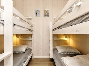 A bunk bed room with wooden walls, two framed pictures, and bedside lamps. - 5 Star Holiday Home in Hadsund (Hadsund)