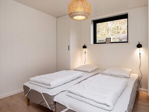 Un dormitorio con cama, dos lámparas de noche, una ventana y una lámpara colgante.