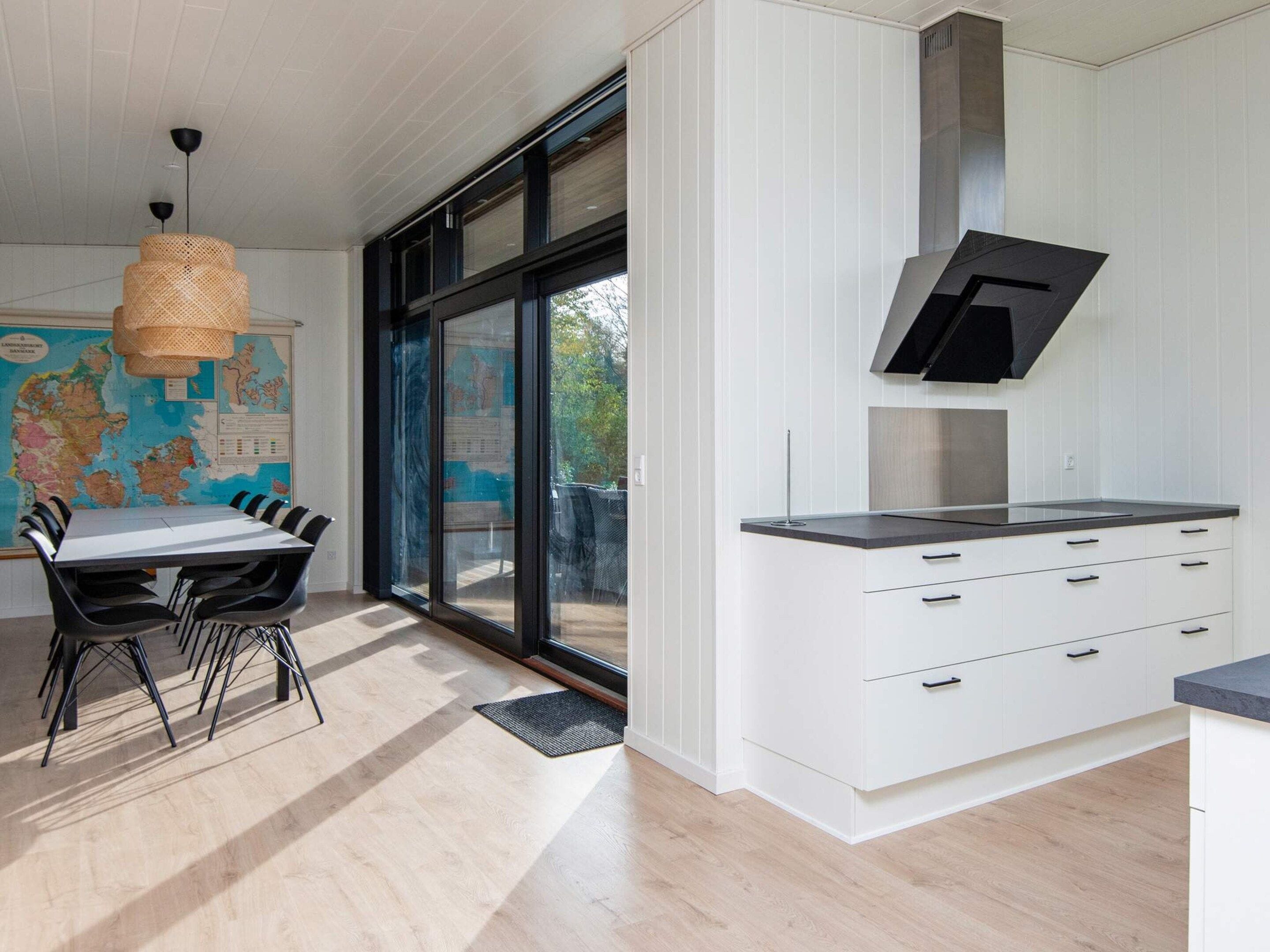 Een moderne keuken met witte kastjes, een zwart aanrecht en een groot raam.
