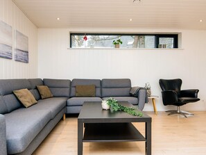 A modern living room with a grey sectional sofa, a black coffee table, and a black armchair. - 5 Star Holiday Home in Ebeltoft (Ebeltoft)