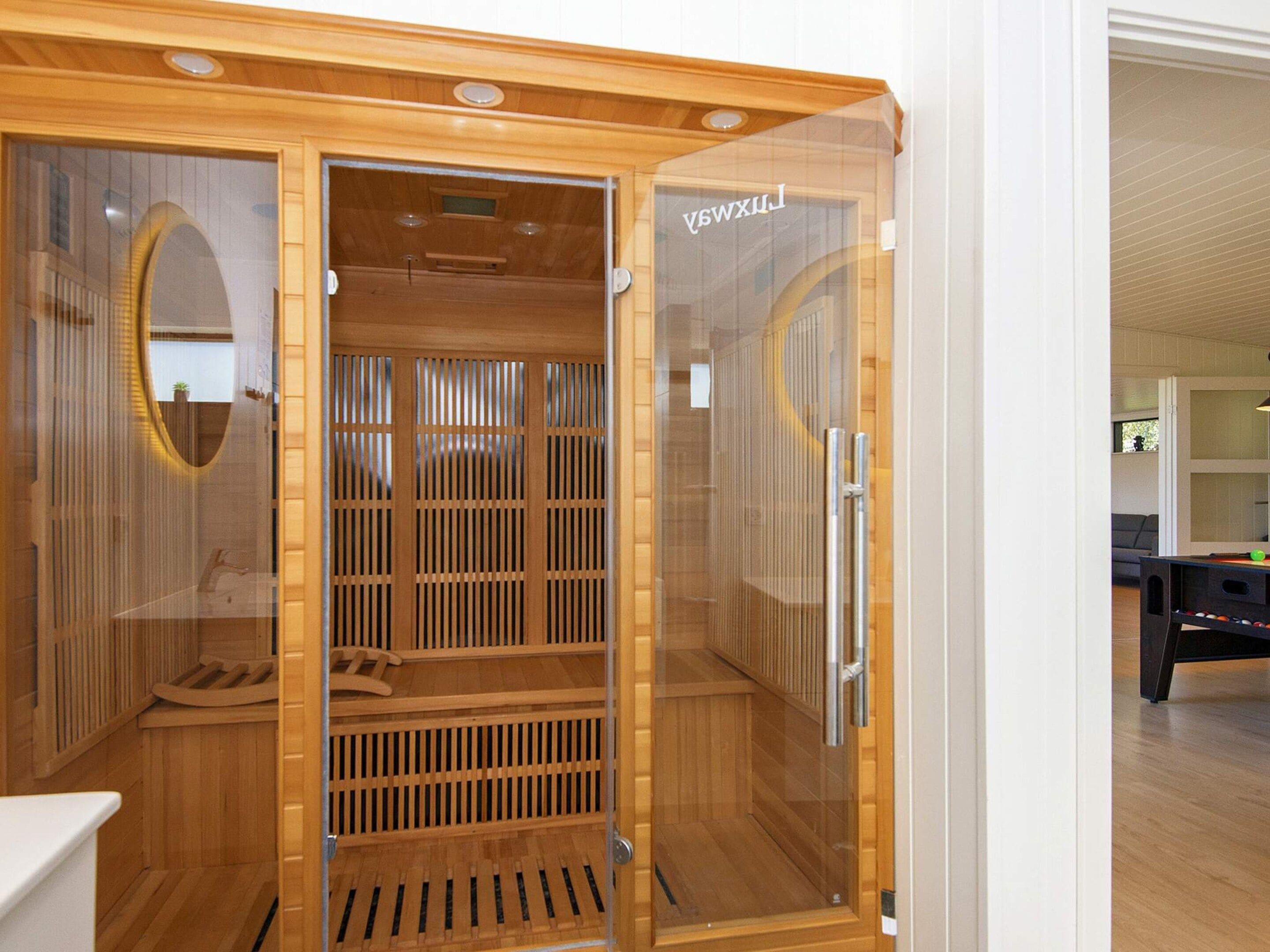 Un sauna avec un intérieur en bois, une porte en verre et un panneau de commande visible.