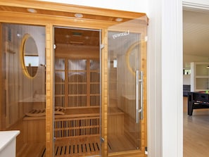 A sauna with a wooden interior, a glass door, and a visible control panel. - 5 Star Holiday Home in Ebeltoft (Ebeltoft)