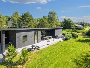Ett modernt hus med en uteplats, utomhusmöbler och en grill.