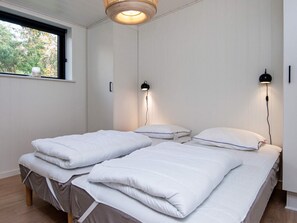 Et soveværelse med to senge, et vindue og to væglamper.