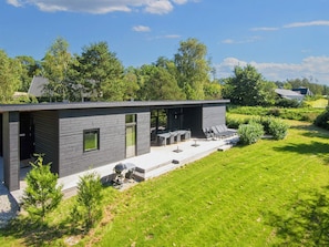 A modern house with a patio area, outdoor seating, and a barbecue grill. - 5 Star Holiday Home in Ebeltoft (Ebeltoft)