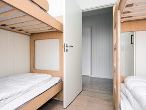 A room with two bunk beds, a wooden door, and a white wall.