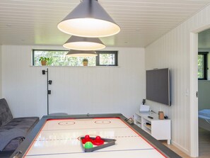 A room with a ping pong table, a sofa, a TV, and a window with plants. - 5 Star Holiday Home in Ebeltoft (Ebeltoft)