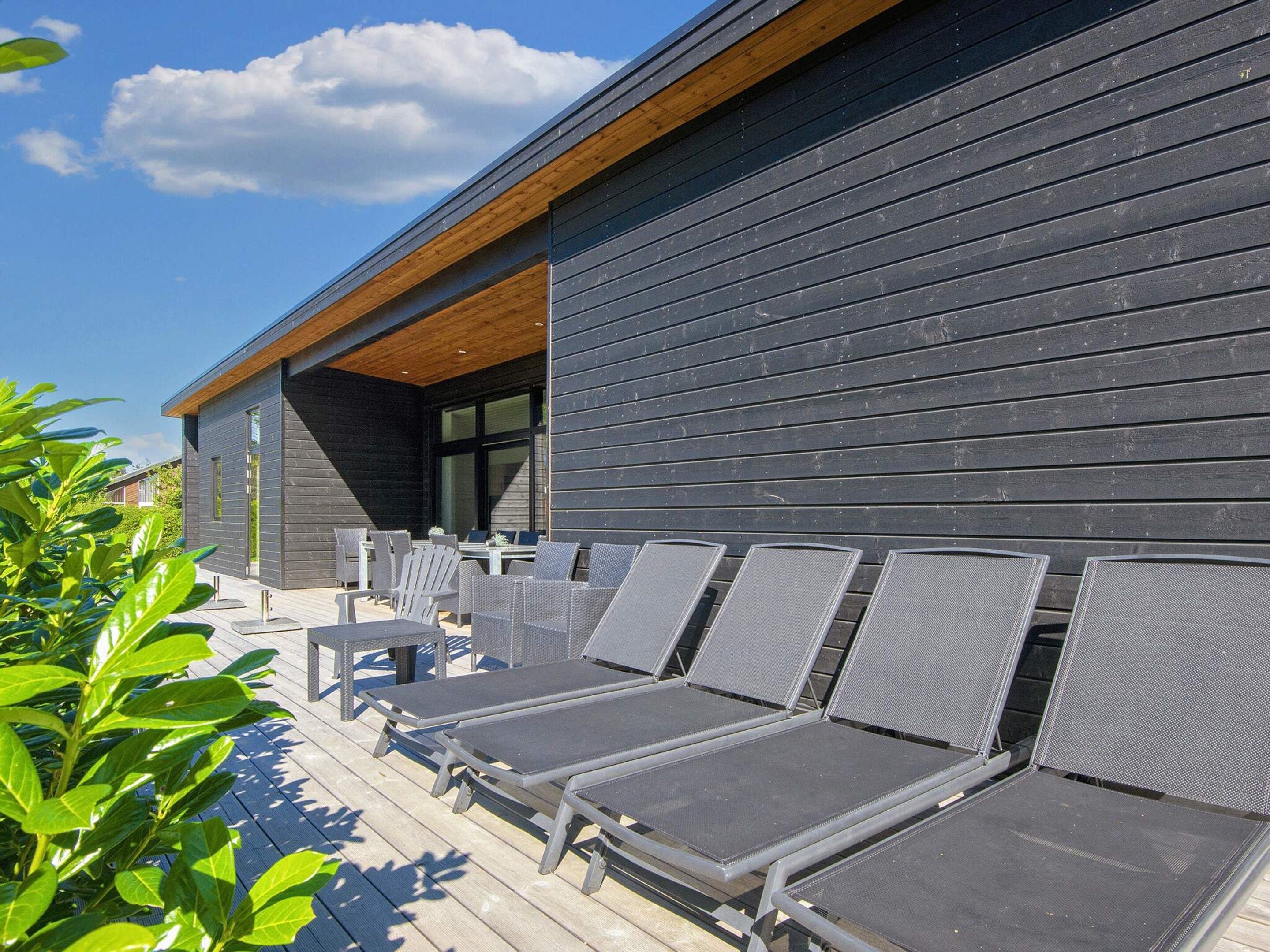 A modern building with a wooden deck and outdoor seating.