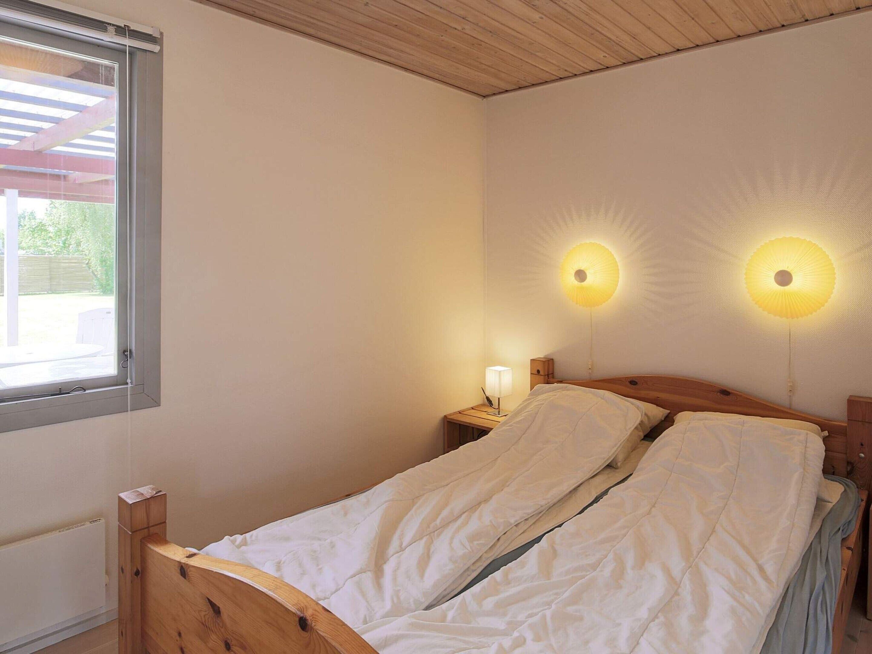 Une chambre à coucher avec un lit en bois, une table de chevet avec une lampe et deux lampes fixées au mur.