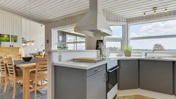 A modern kitchen with a large island, stainless steel appliances, and a view of the outdoors.