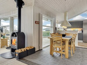 Une cuisine moderne dotée d’un grand îlot central, d’un coin repas avec des chaises en bois et d’un poêle à bois.
