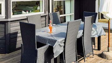 An outdoor dining area with wicker chairs and a table, set against a wooden deck.