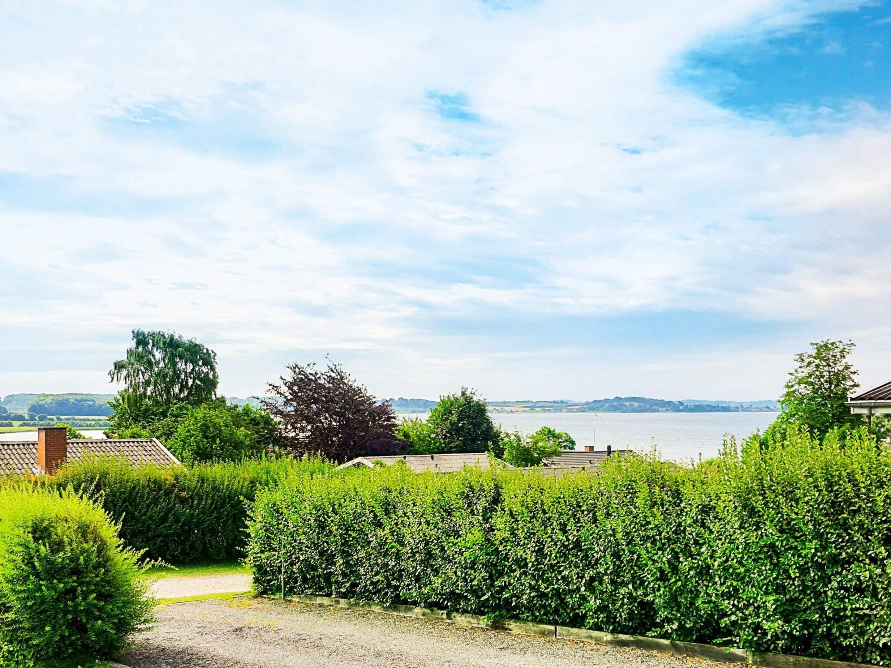A residential area with a view of a body of water, surrounded by greenery and a clear sky.