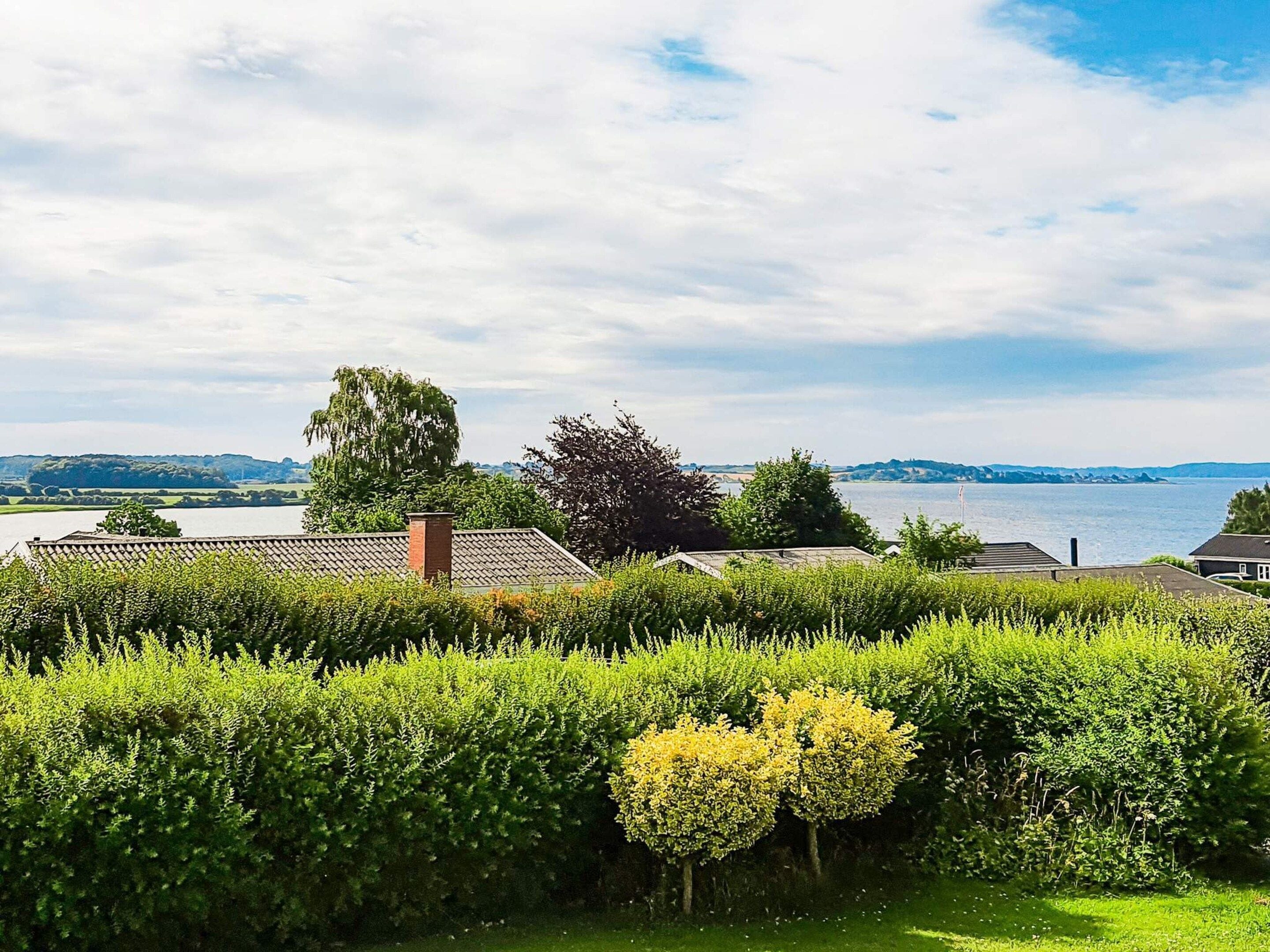 A residential area with a view of a lake, surrounded by well-maintained hedges and trees.