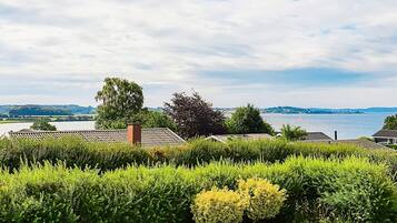 A residential area with a view of a lake, surrounded by well-maintained hedges and trees.