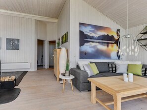 En moderne stue med et stort billede, et træbord og en grå sofa.