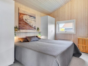 Une chambre à coucher avec un lit, un tableau, une fenêtre et un radiateur.