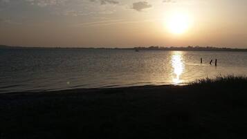 A sunset over a calm body of water with a distant shoreline silhouette.
