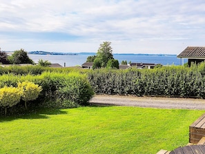 Une zone herbeuse offrant une vue sur un lac et des collines lointaines.