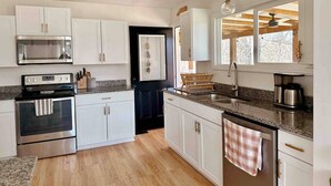 Una cocina moderna con gabinetes blancos, electrodomésticos de acero inoxidable y piso de madera.
