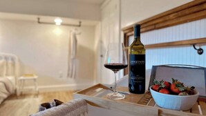 Un salón acogedor con una mesa de madera que sostiene una botella de vino, una copa y un bol de fresas.