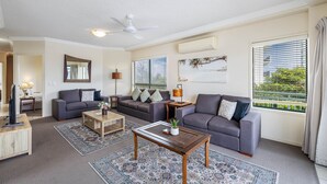 A modern living room with two grey sofas, a wooden coffee table, a TV, and a ceiling fan.