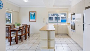 A modern kitchen with a wooden dining table, white cabinets, and a built-in island.