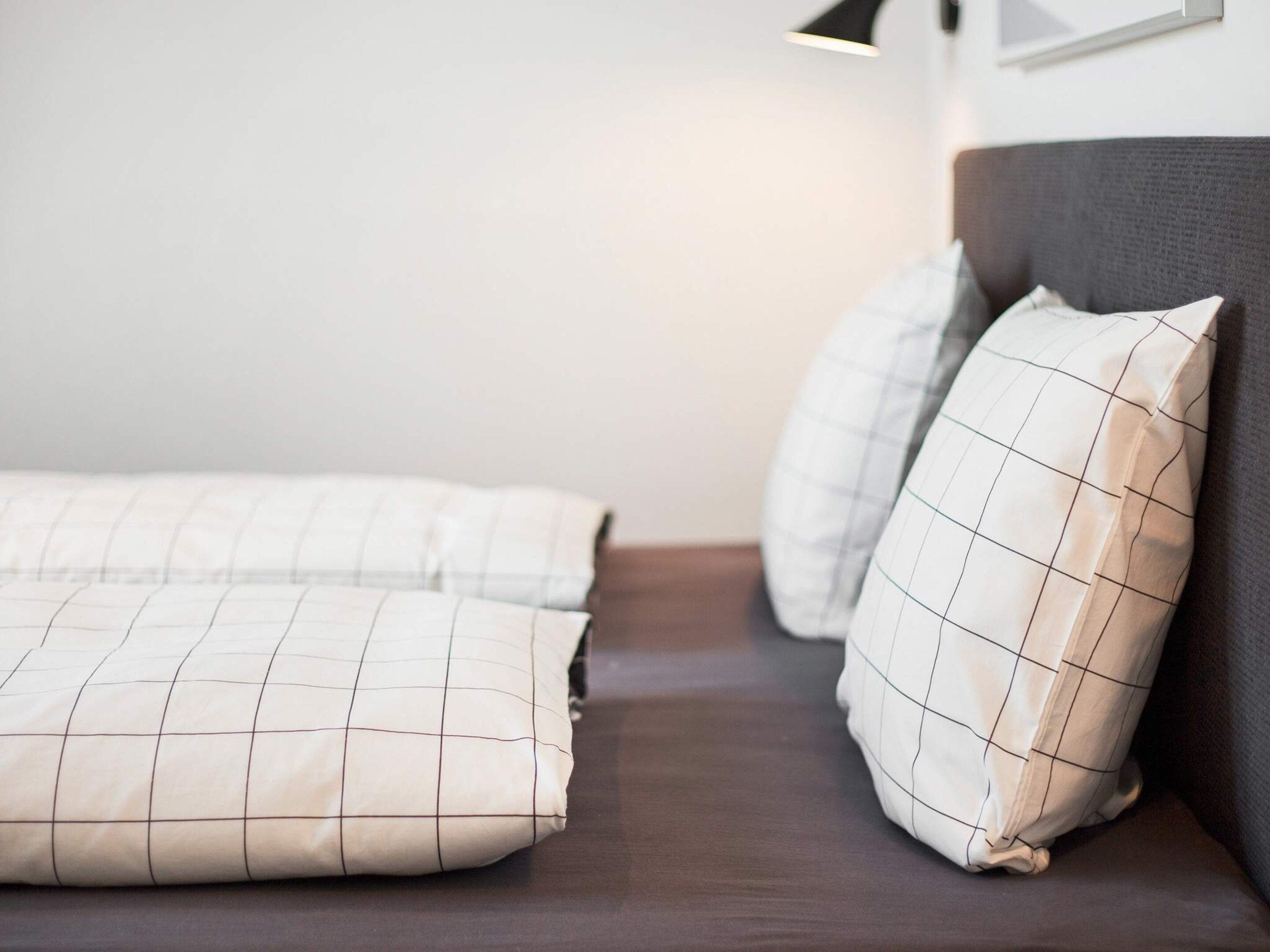 Una cama con cabecera oscura y dos almohadas con diseño de cuadrícula.