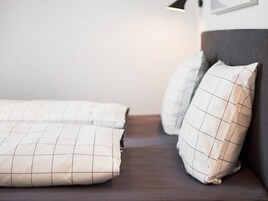 Una cama con cabecera oscura y dos almohadas con diseño de cuadrícula.