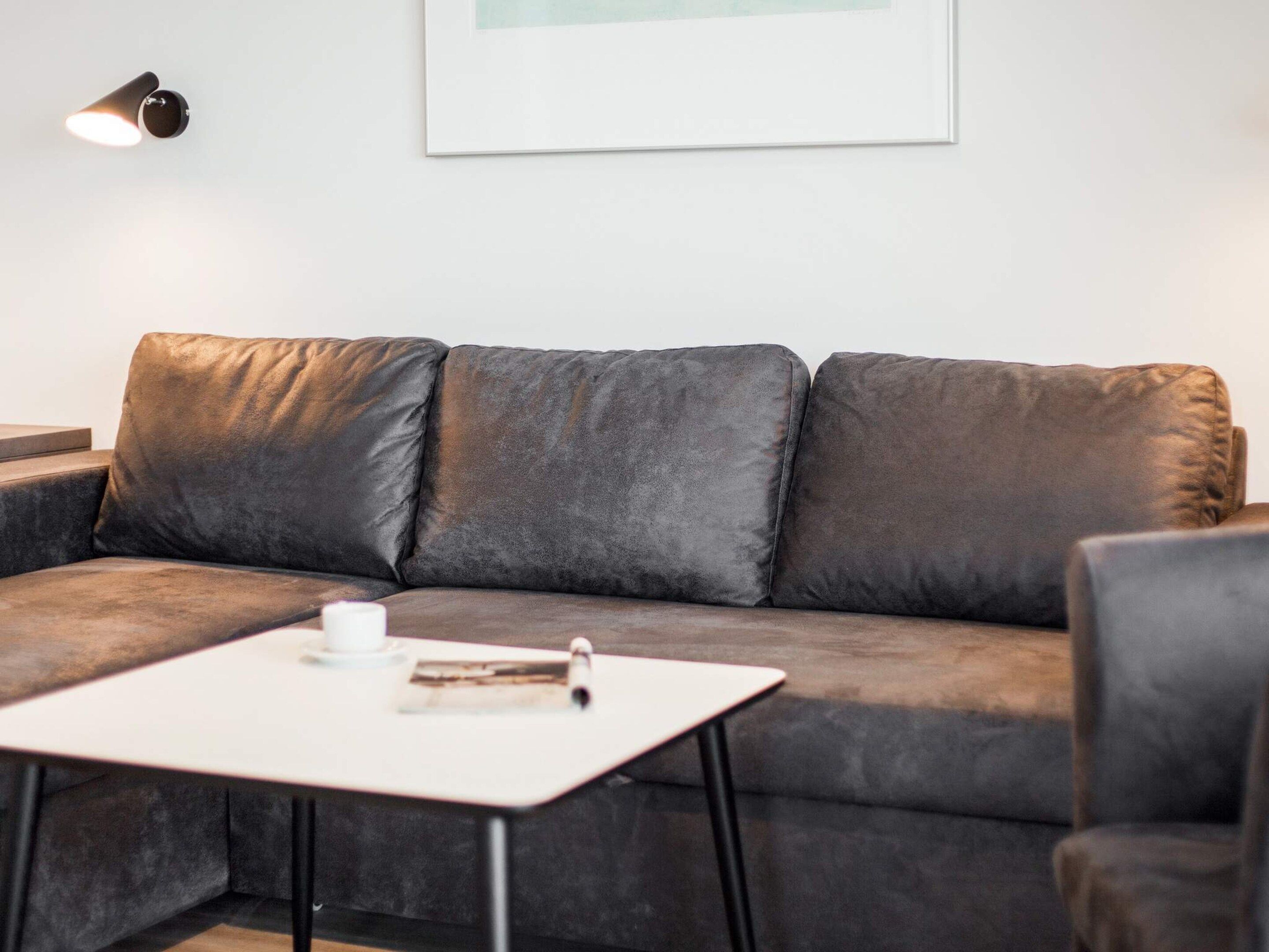 Ein modernes Wohnzimmer mit einem dunkelbraunen Ledersofa, einem weißen Couchtisch und einer schwarzen Stehlampe.