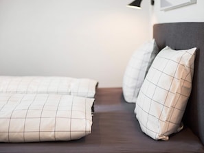 Ein Bett mit dunkelbrauner Kopfteil und zwei Kissen mit Rastermuster.