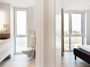 A modern bathroom with a toilet, sink, and hairdryer mounted on the wall. - Exklusive Auszeit mit Meerblick (Wendtorf)