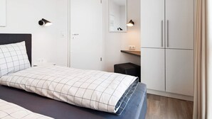 A bedroom with a bed, a wardrobe, a mirror, and a nightstand. - 5 Star Holiday Home in Wendtorf (Wendtorf)