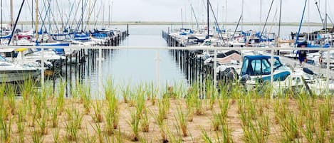 Ein Yachthafen mit vertäuten Booten, umgeben von Sand und Gras.
