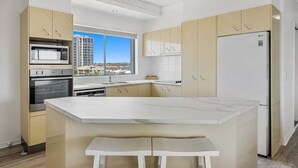 Una cocina moderna con una isla central, electrodomésticos integrados y vistas a la ciudad.